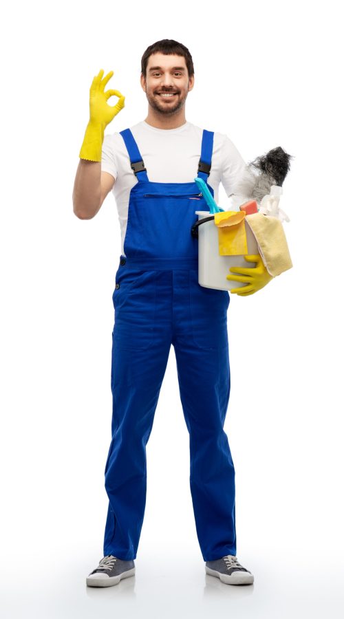 profession, service and people - happy smiling male worker or cleaner in overal and gloves with cleaning supplies showing ok hand sign over white background